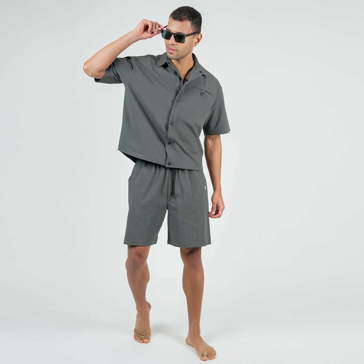 Man wearing a gray shirt and shorts set on a white background