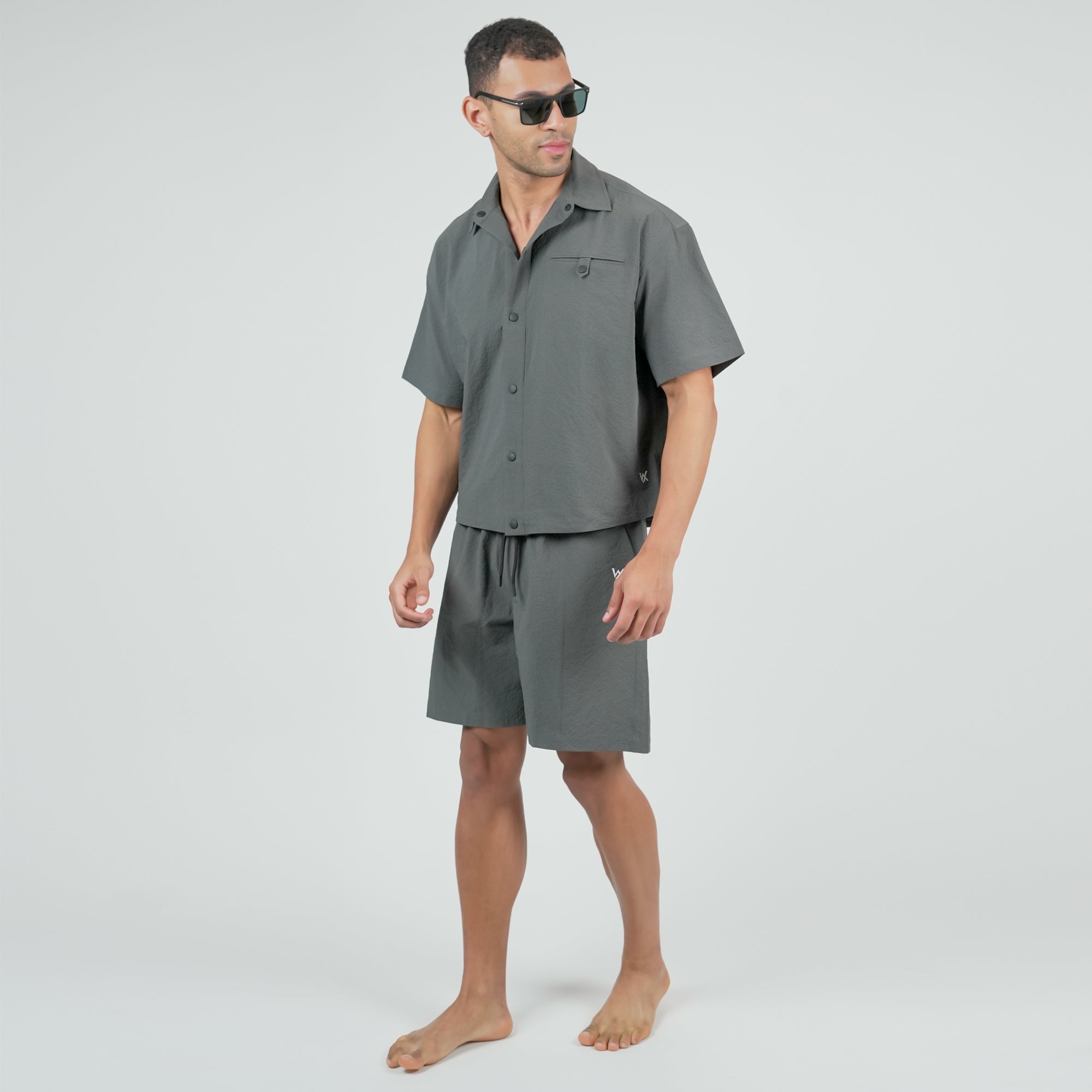 Man wearing a gray shirt and shorts set on a white background